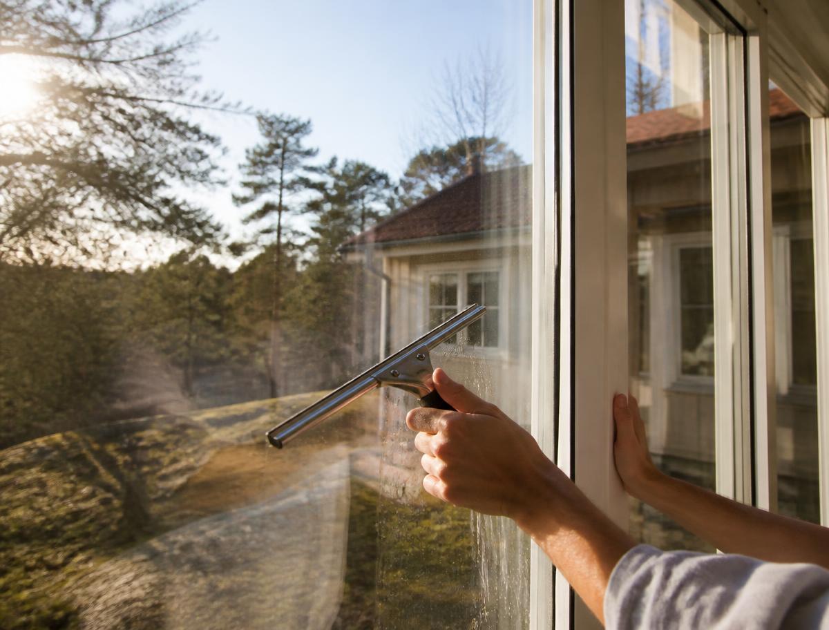 Fönsterputs med skrapa på ett fönster i solljus